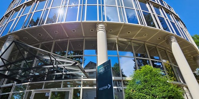 Modern office building with glass facade, and a sign reading 'Building 1 – Vector', blue sky in the background