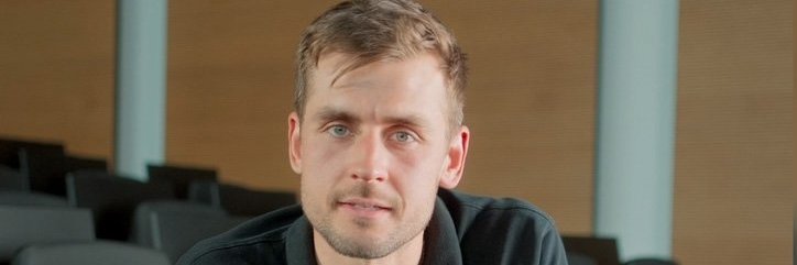 Ein Vector-Mitarbeiter in einem schwarzen Sweatshirt sitzt in einem modernen Auditorium.