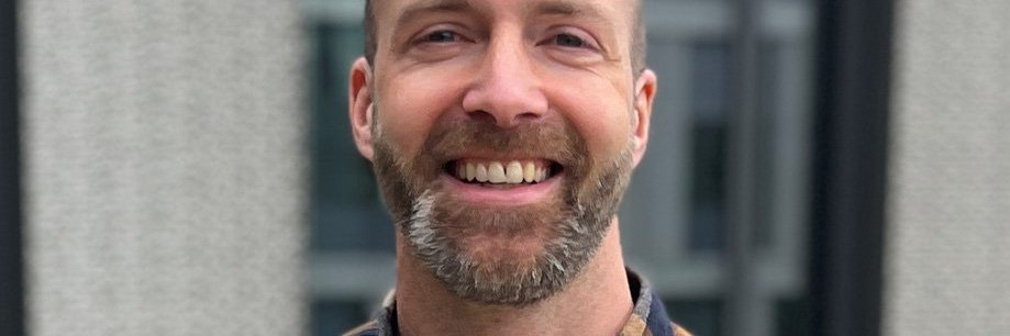 Vector-Mitarbeiter in einer Portraitaufnahme vor dem Firmengebäude mit modernen Fassade.