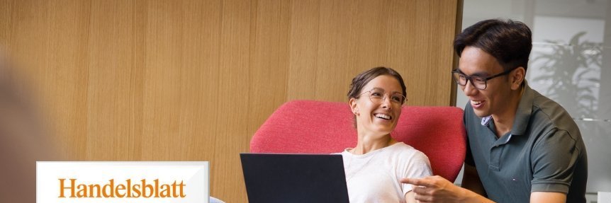 Zwei Personen arbeiten gemeinsam am Laptop auf roten Sesseln, links im Bild das Handelsblatt Fair Company 2024 Zertifikat