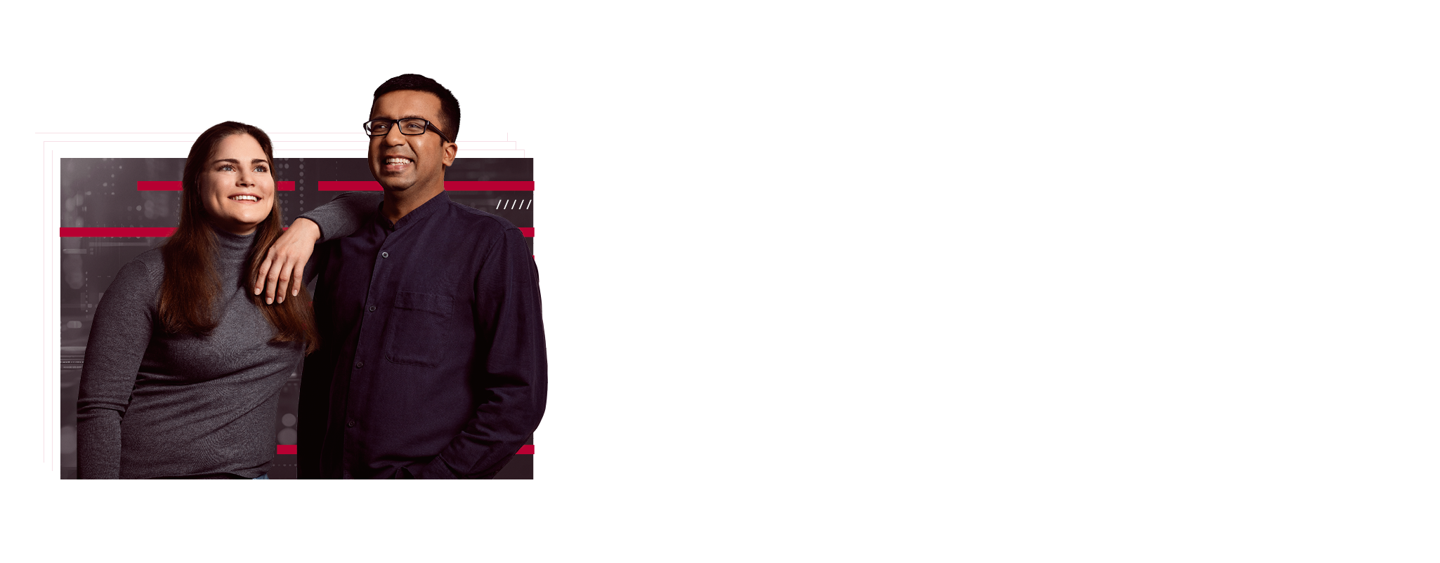 Two employees are standing next to each other. She has one arm on her colleague's shoulder. Both are smiling and appear content.