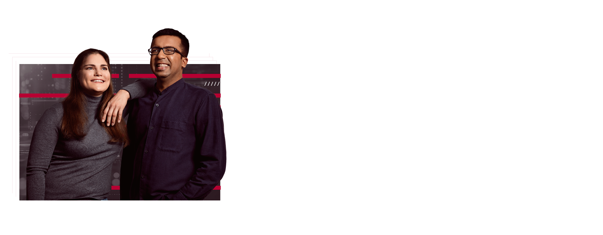 Two employees are standing next to each other. She has one arm on her colleague's shoulder. Both are smiling and appear content.