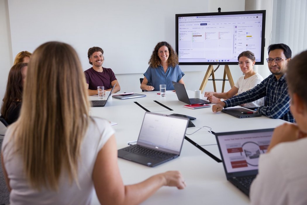 Teammeeting im modernen Büro mit Laptops und Präsentation auf Bildschirm