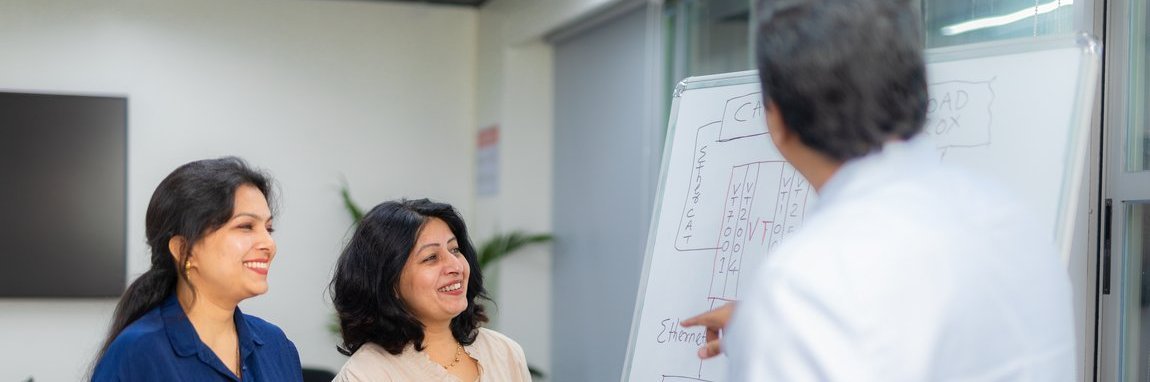 Three employees in front of a white board with technical graphics about