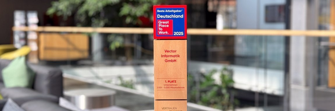 Modern office environment with comfortable seating and a green plant in the background. In the foreground is a wooden award with the title "Best Employer Germany - Great Place to Work 2025".