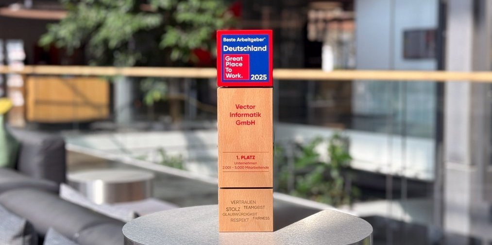 Modern office environment with comfortable seating and a green plant in the background. In the foreground is a wooden award with the title "Best Employer Germany - Great Place to Work 2025".