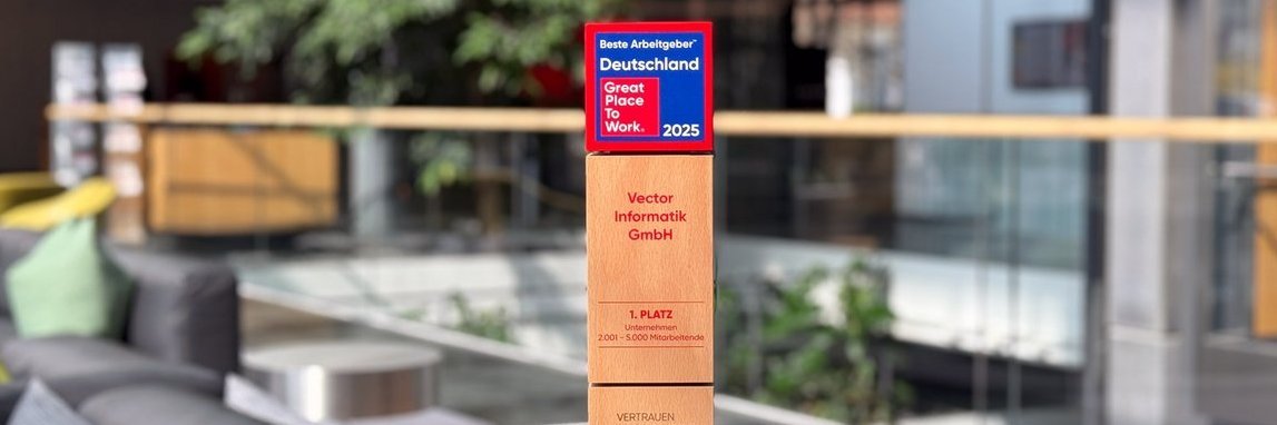 Modern office environment with comfortable seating and a green plant in the background. In the foreground is a wooden award with the title "Best Employer Germany - Great Place to Work 2025".