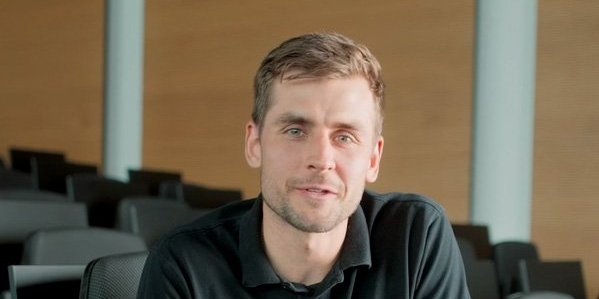 A Vector employee wearing a black sweatshirt is sitting in a modern auditorium.