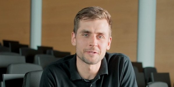 Ein Vector-Mitarbeiter in einem schwarzen Sweatshirt sitzt in einem modernen Auditorium.