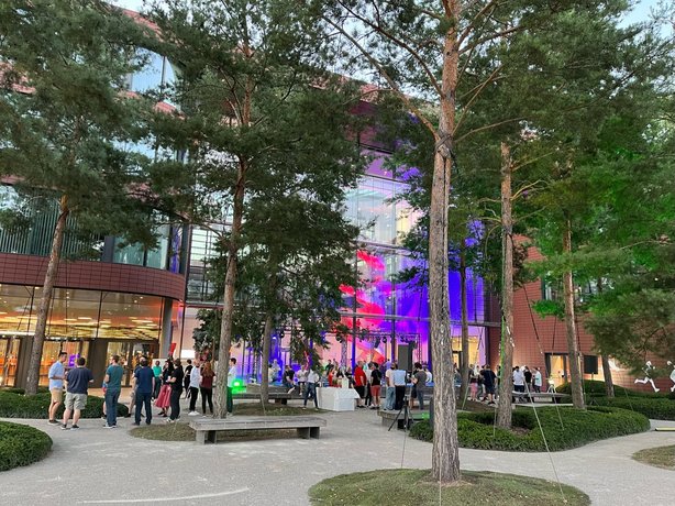 Menschen vor dem Vector Hauptgebäude mit bunter Beleuchtung und Bäumen – stimmungsvolle Abendveranstaltung im urbanen Umfeld