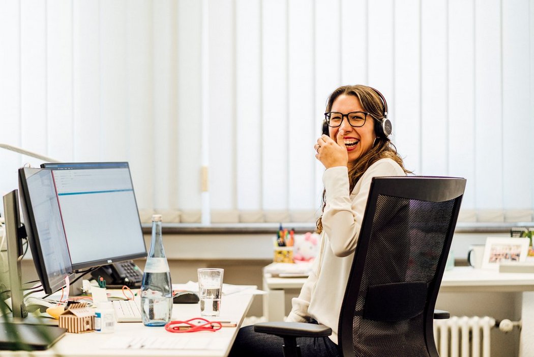 Vector employee sitting in front of her PC screen laughing 