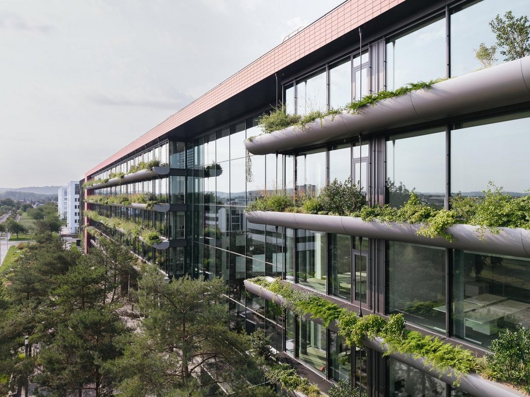 Begrünte Außenfassade des modernen Bürogebäudes mit großen Fensterflächen.