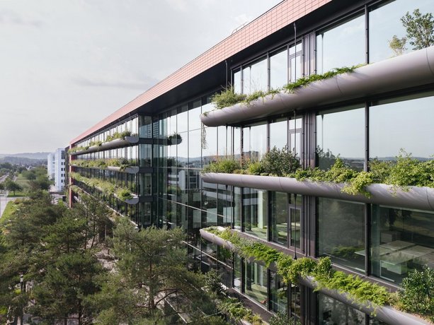 Begrünte Außenfassade des modernen Bürogebäudes mit großen Fensterflächen.