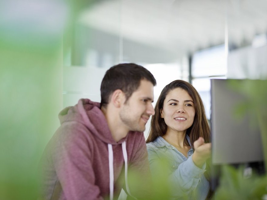 Two Vector employees sitting in front of a PC screen and having a friendly chat  
