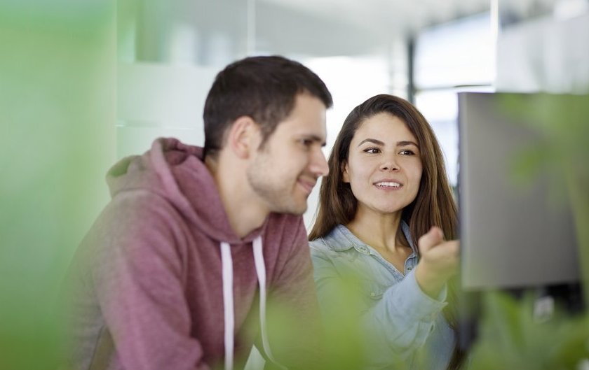 Two Vector employees sitting in front of a PC screen and having a friendly chat  
