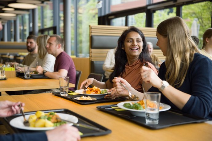 Vector Mitarbeitende sitzen an einem Tisch und verspeisen ein leckeres Mittagessen.