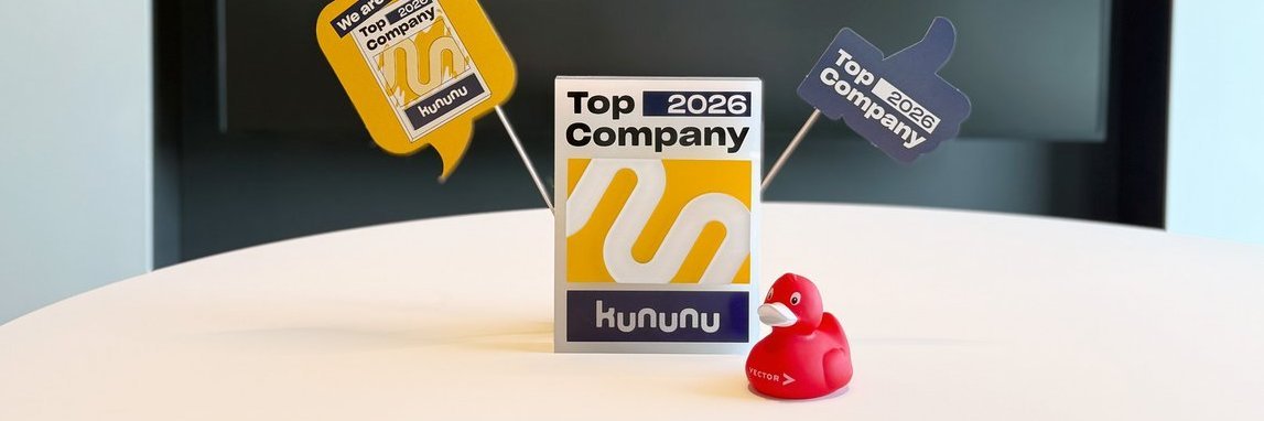 kununu-Pokal für die Auszeichnung als Top Company 2026 mit einer roten Quietscheente im Vordergrund, im Hintergrund sind festliche Wimpel.