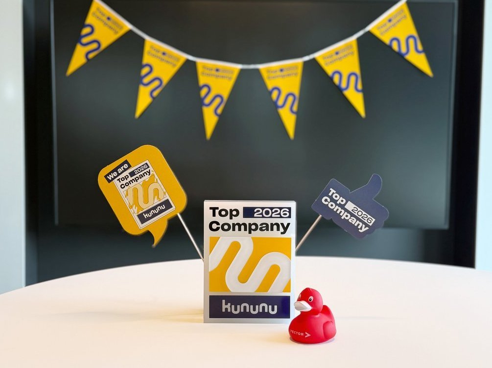 kununu trophy for the Top Company 2026 award with a red rubber duck in the foreground and festive pennants in the background.