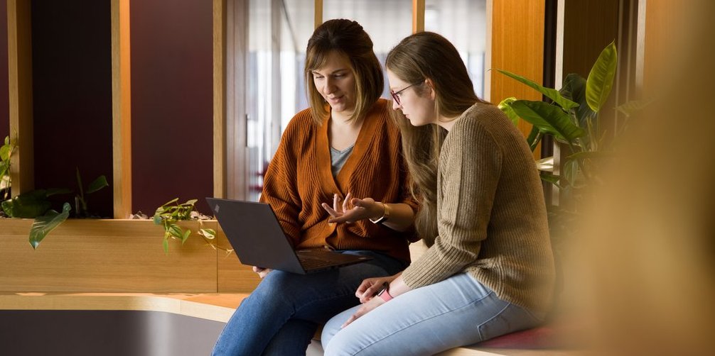 Zwei Mitarbeiterinnen diskutieren am Laptop