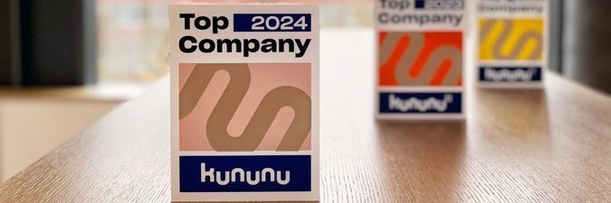 kununu-Auszeichnungen der Jahre 2022, 2023 und 2024 auf einem Holztisch eines Vector-Gebäudes