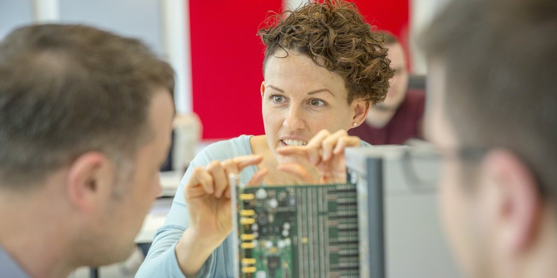 9.000 Kunden in 76 Ländern werden umfassend betreut. Vector Mitarbeitende vor einer Test-Hardware