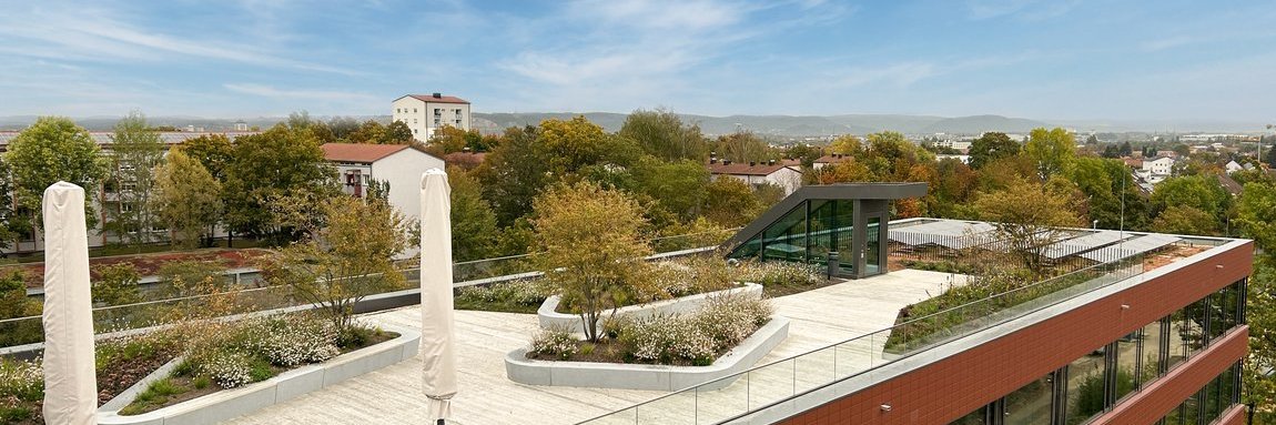 New building in Regensburg with modern terrace, sun umbrellas, and blue sky 