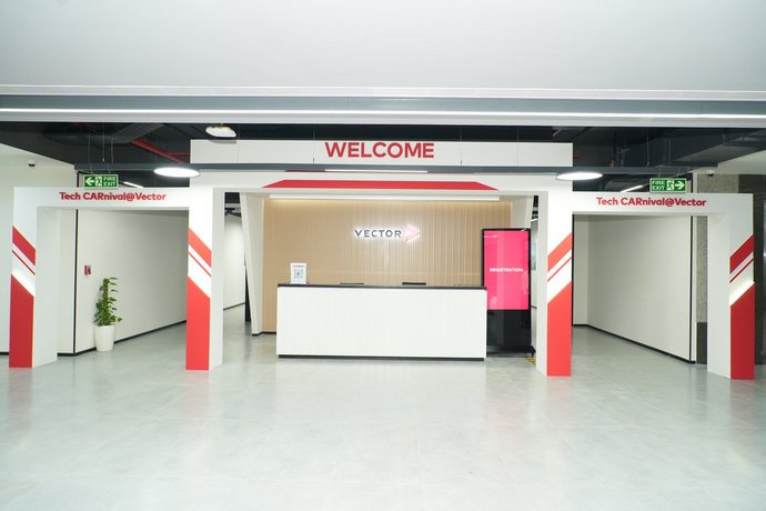 Bright reception area with large welcome sign, clean lines, and modern vector counter in the center. The open design and red and white accents convey a professional, high-quality first impression.