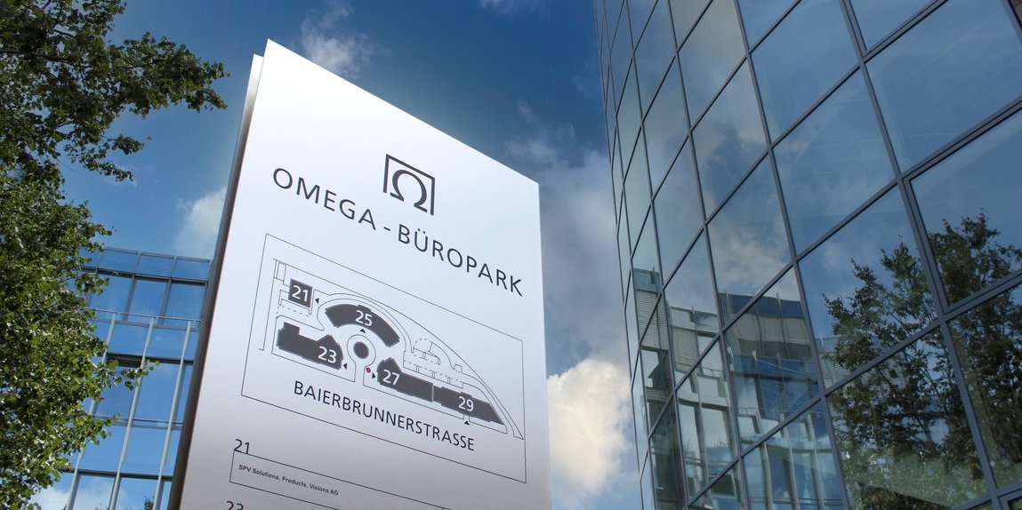 Omega Business Park sign with site map and company list on Baierbrunnerstraße, surrounded by modern glass buildings and blue sky