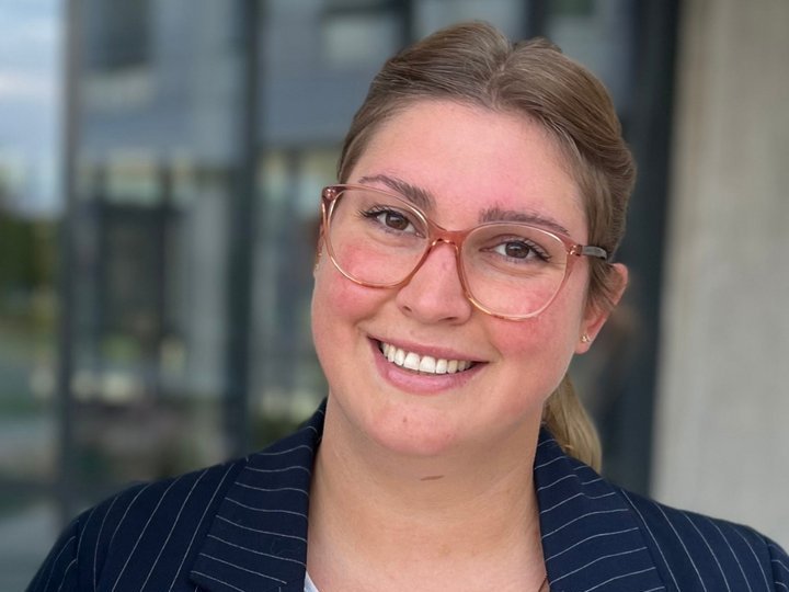 Portrait shot of a Vector employee. She smiles into the camera in front of a blurred office background.