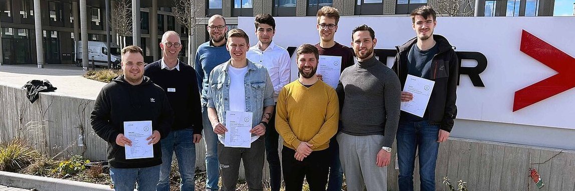 Foto von Studierenden der Hochschule Pforzheim mit AUTOSAR-Zertifikat in den Händen vor einem Gebäude der Vector Informatik GmbH