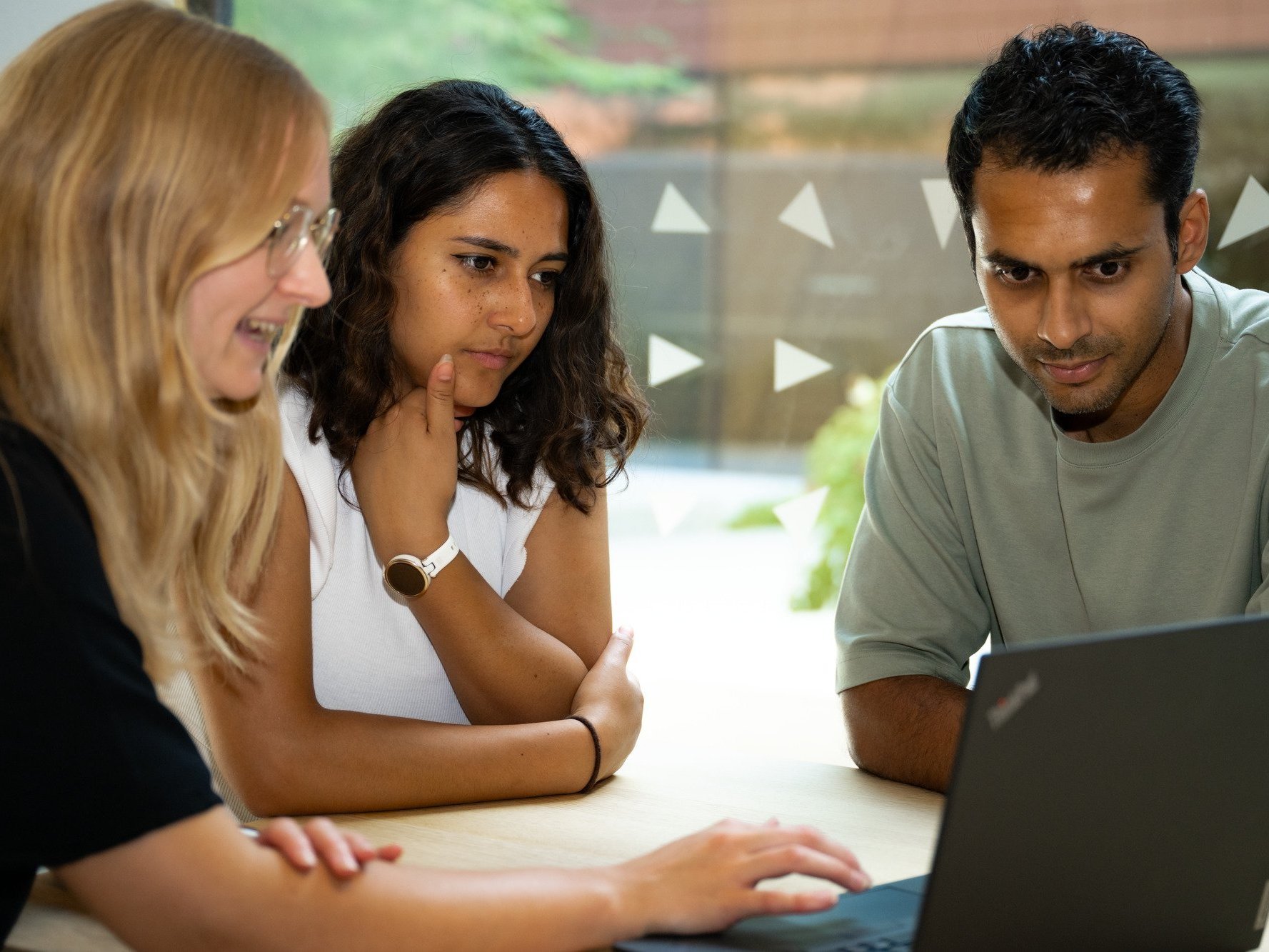 3 Studenten schauen konzentriert in einen Laptop
