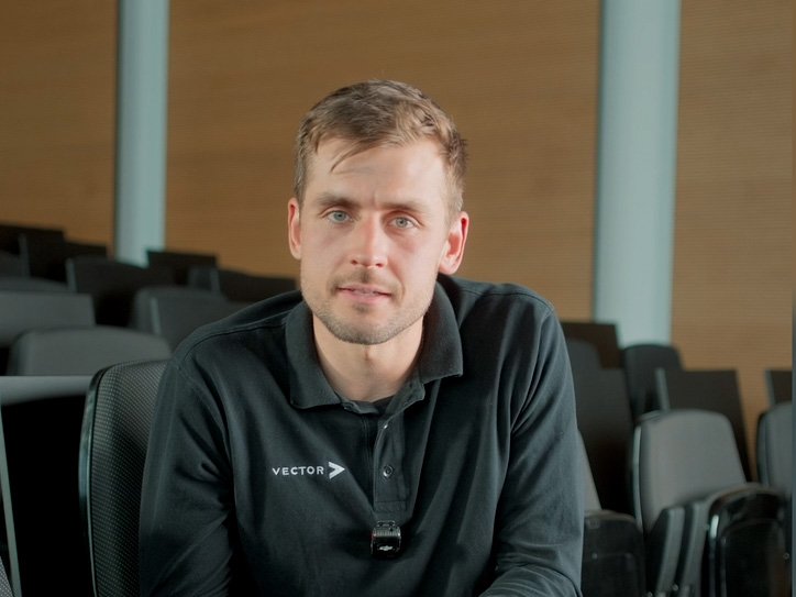 Ein Vector-Mitarbeiter in einem schwarzen Sweatshirt sitzt in einem modernen Auditorium.